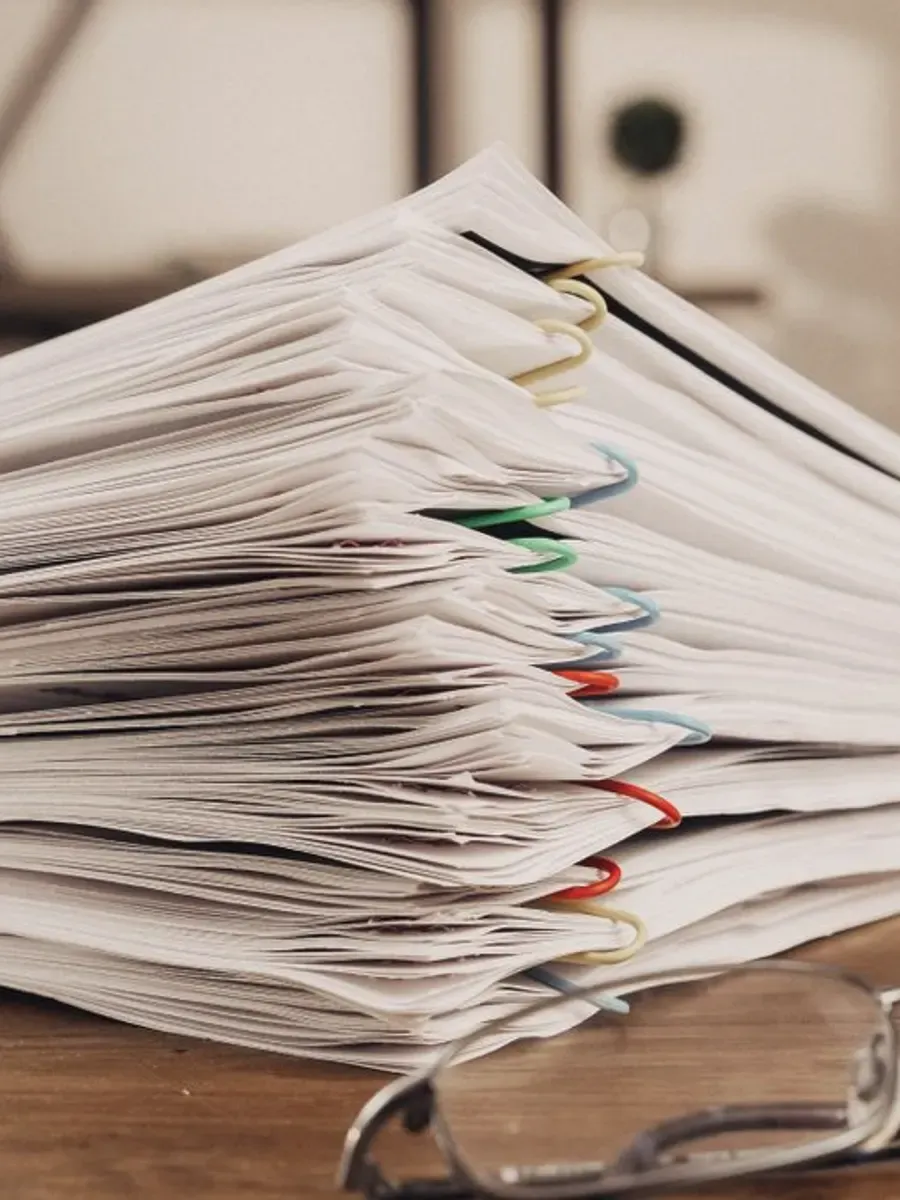 Pile de documents comptables agrafés posée sur un bureau.