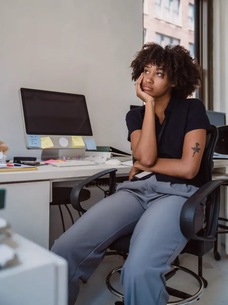 Employée songeuse à son poste de travail encombré de notes.